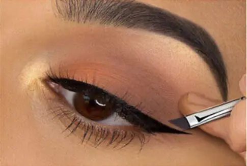 Closeup of eye with eyeliner brush.
