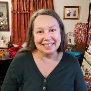 A woman smiling in front of a room full of pictures.