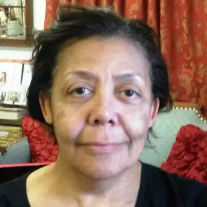 A woman sitting in a living room with a laptop.