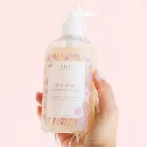 A hand holding a bottle of Farmhouse Fresh Pink Moon Body Wash and Bubble Bath.