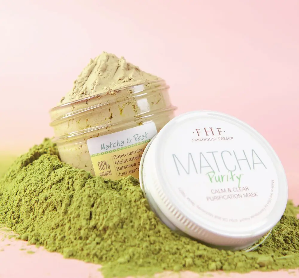 A jar of matcha powder on top of a pink background.