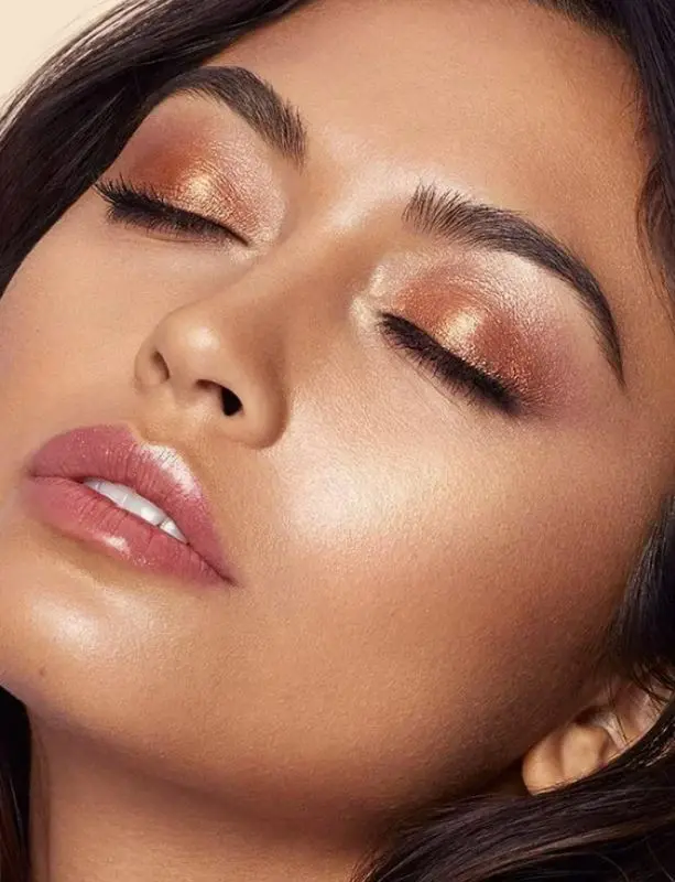 Woman with bronze eyeshadow and glossy lips.
