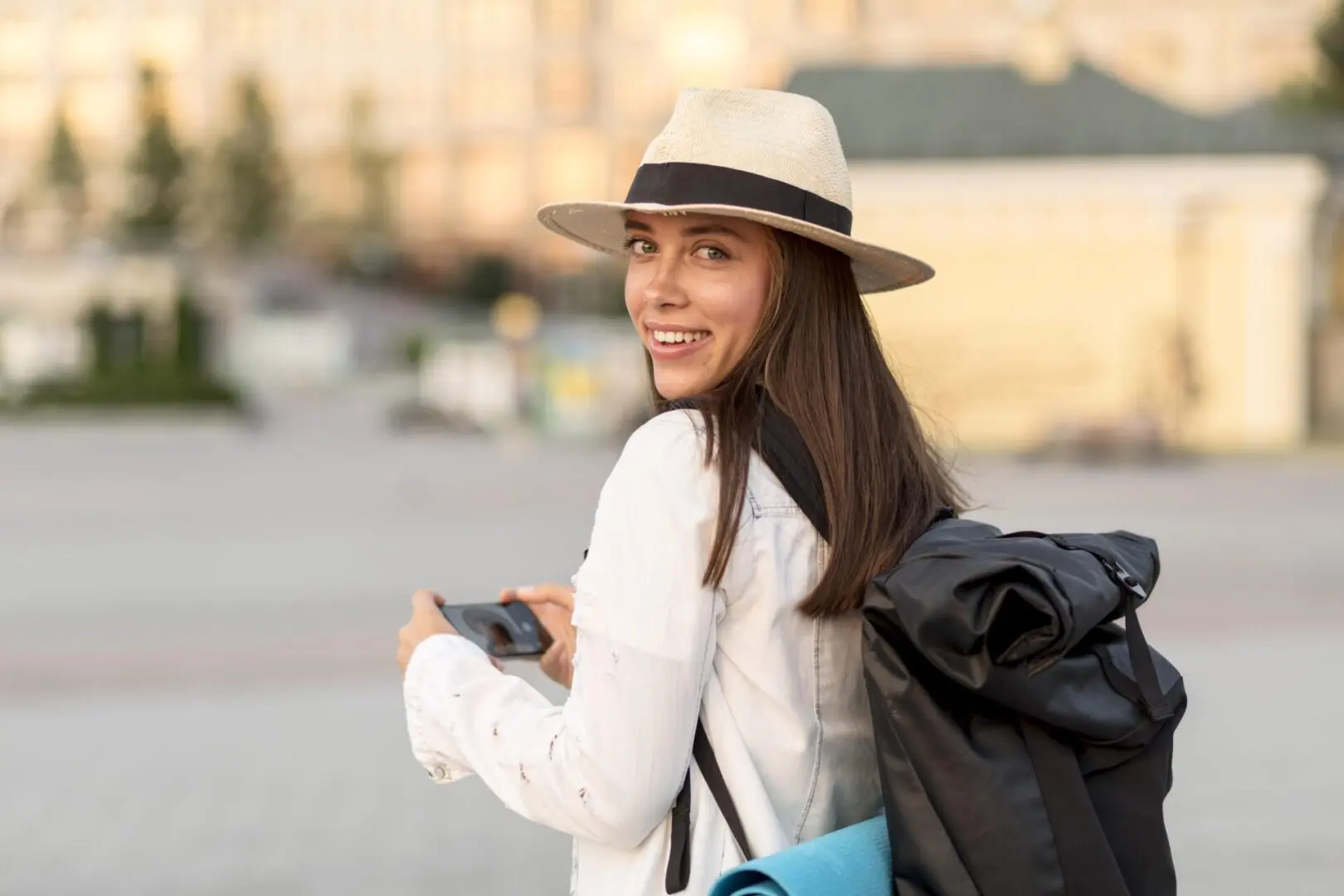 Young woman smiling, wearing a hat, outdoors.