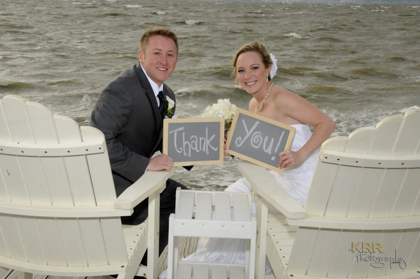 Newlyweds holding thank you signs.