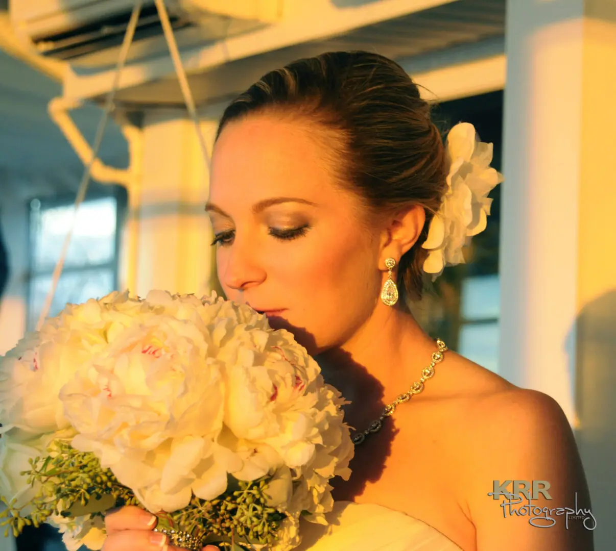 Bride smelling white peony bouquet.