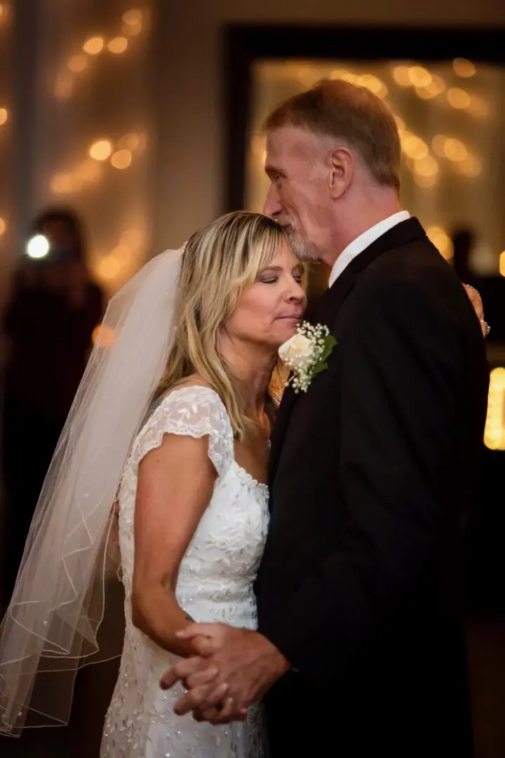Father kisses bride at wedding.