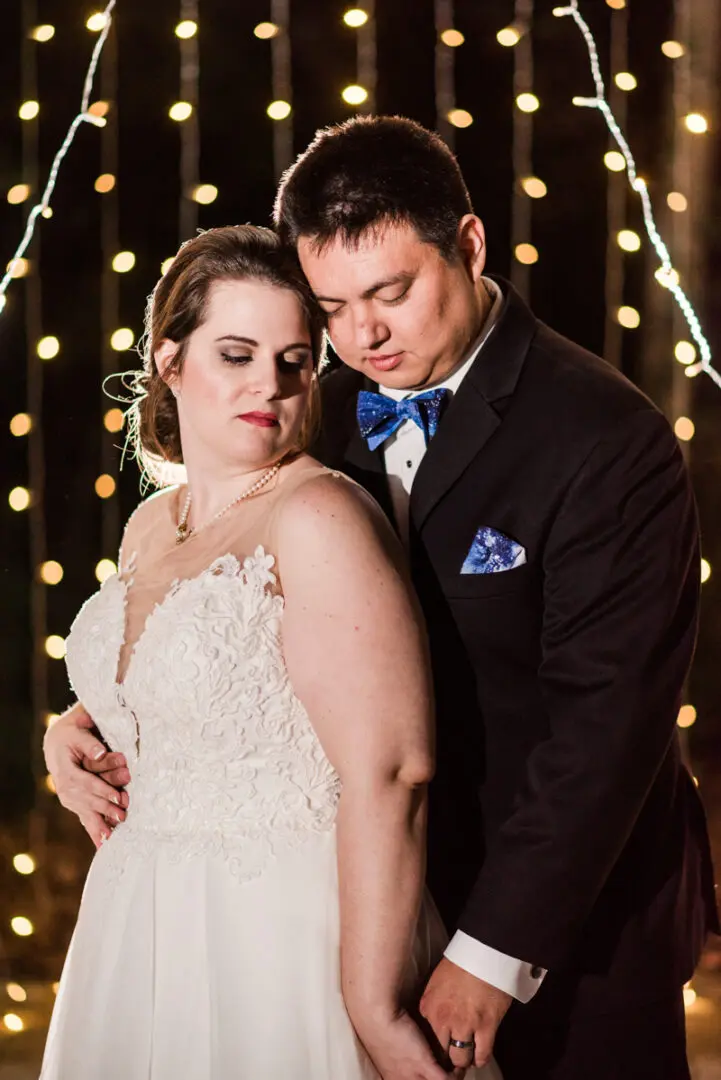 Bride and groom embrace, wedding lights.