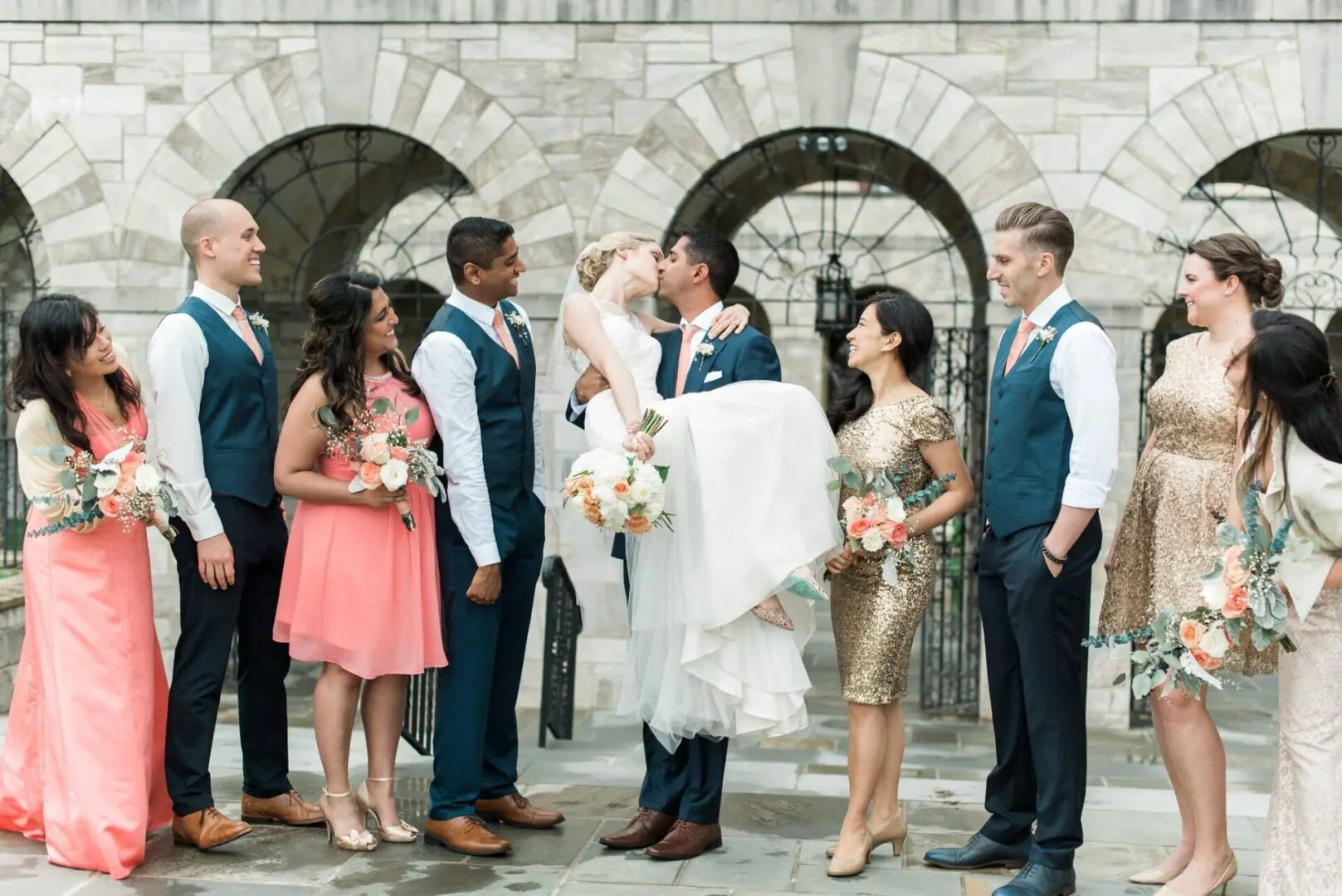 Bride and groom kissing; wedding party.