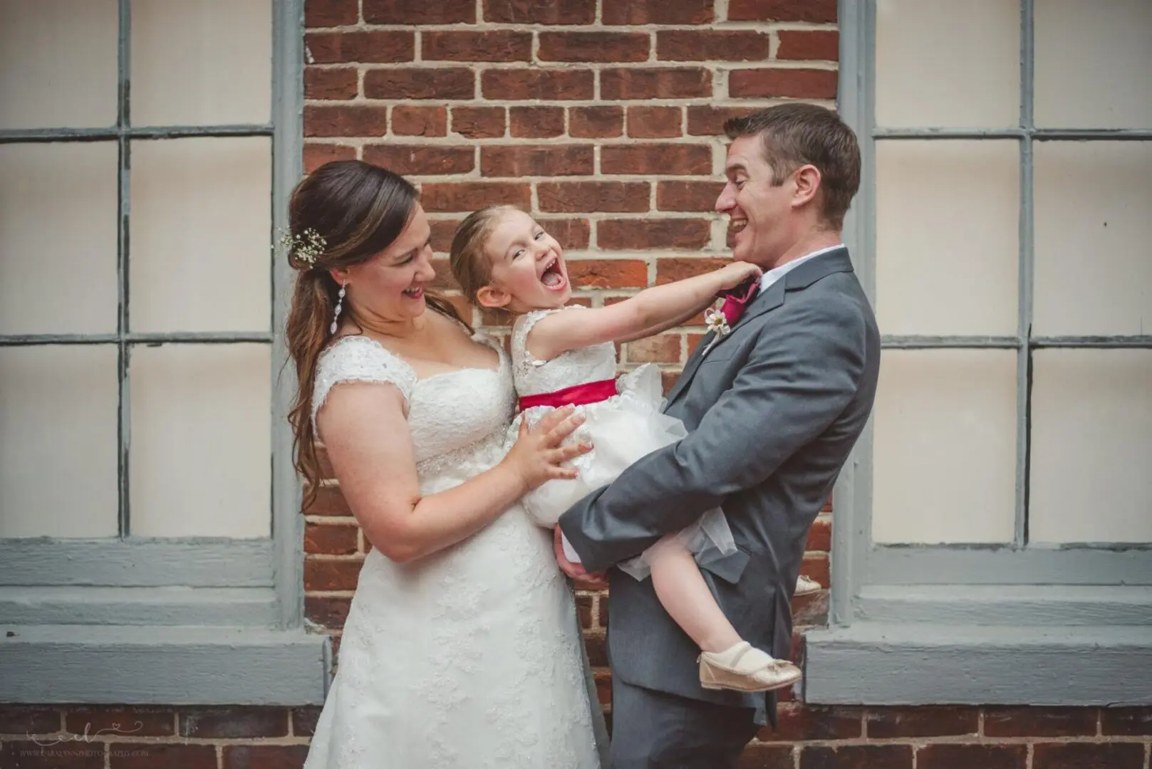 Bride, groom, and flower girl laughing.