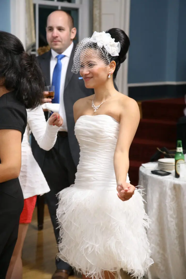 Bride in short white feathered dress.