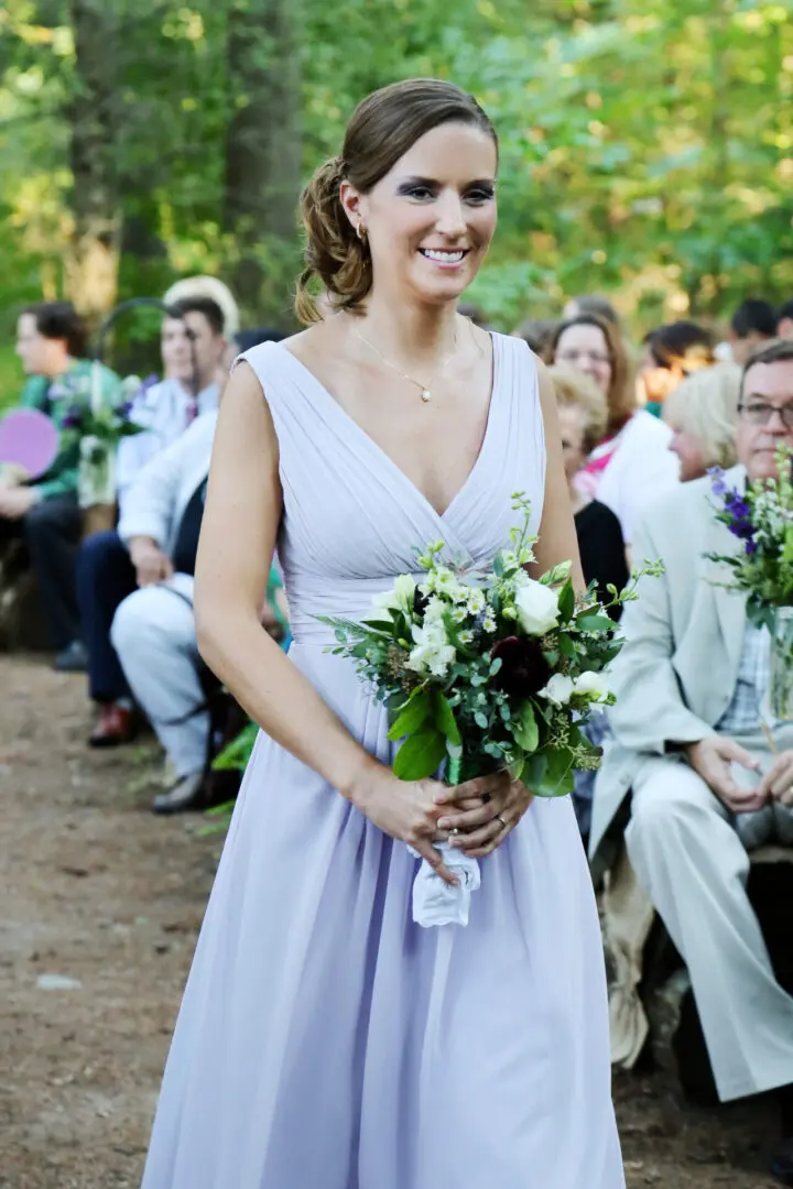 Bridesmaid in lavender dress holds bouquet.