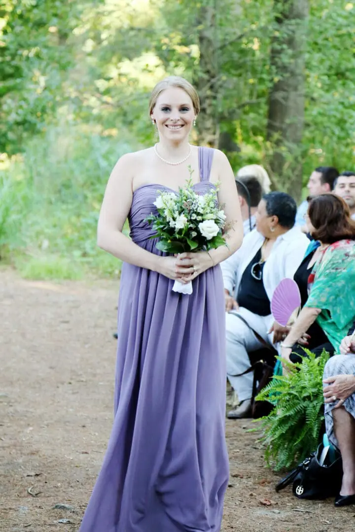 Bridesmaid in lavender dress holding flowers.