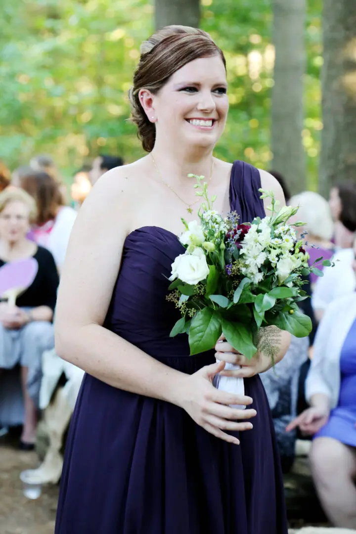 Smiling bridesmaid holding bridal bouquet.