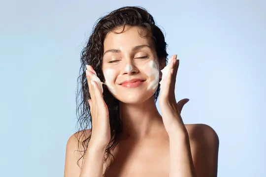 Woman washing face with foam cleanser.