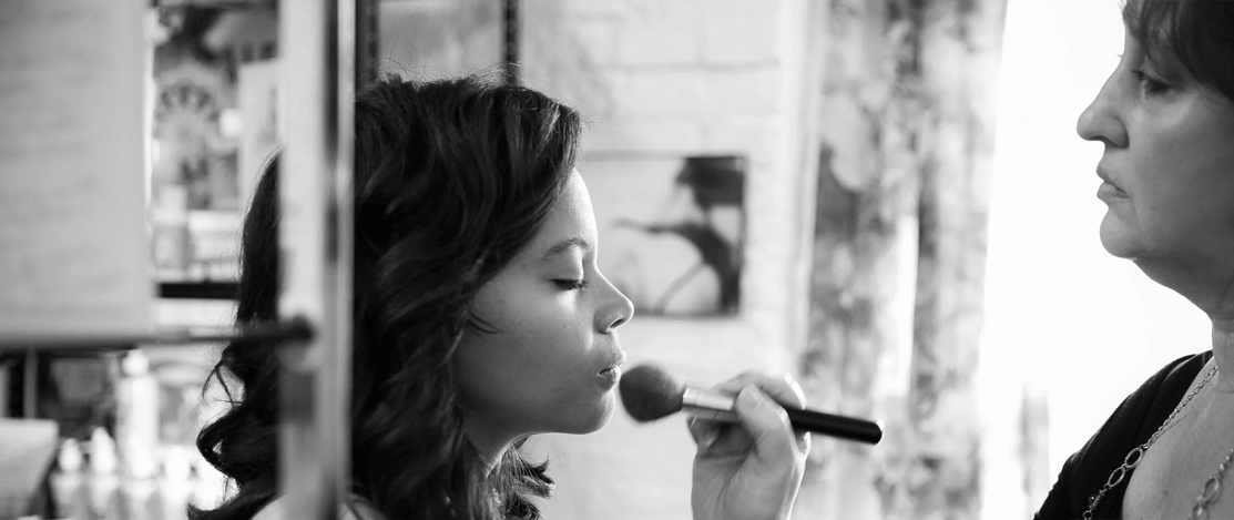 Young bride applying wedding make-up by make-up artist