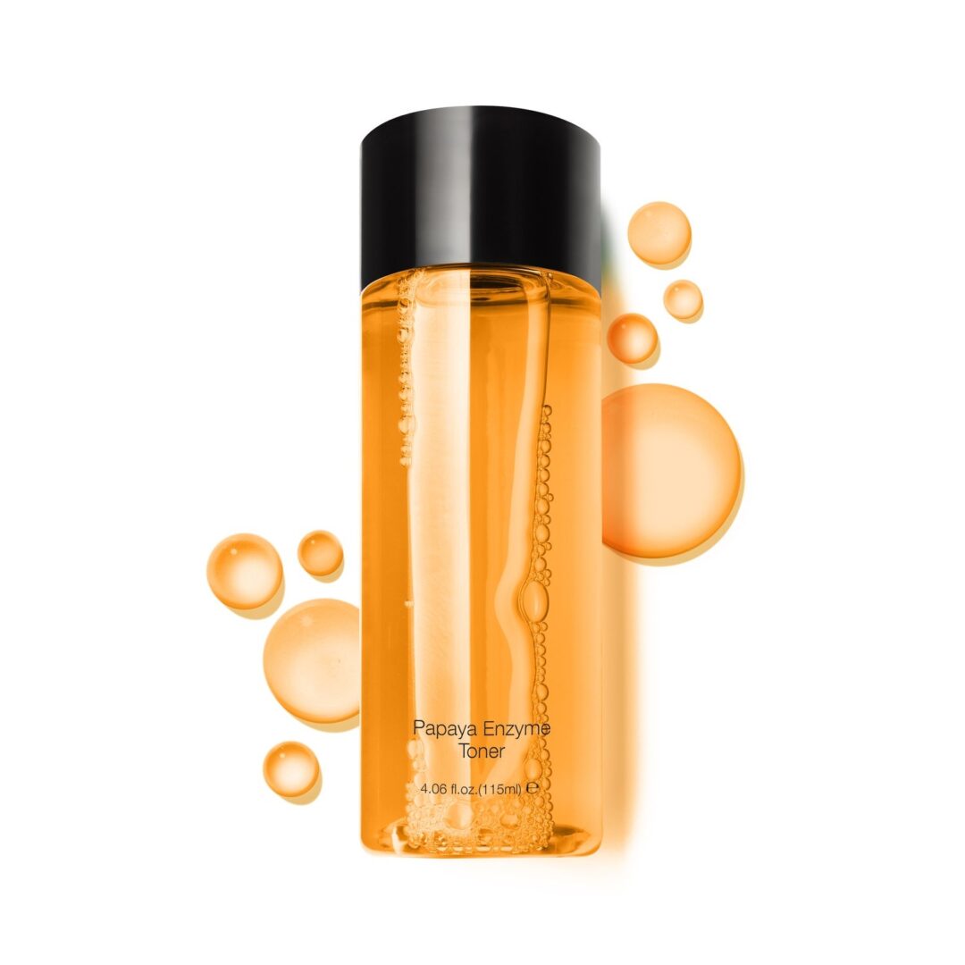 A bottle of facial cleanser with orange bubbles on a white background.