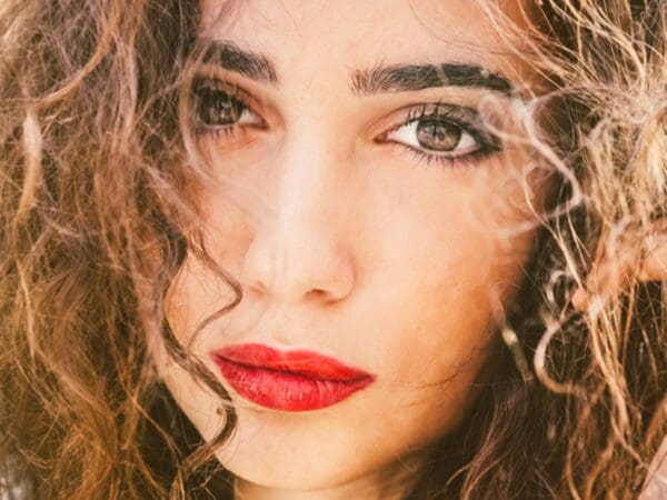 Close-up of woman with red lipstick and curly hair.