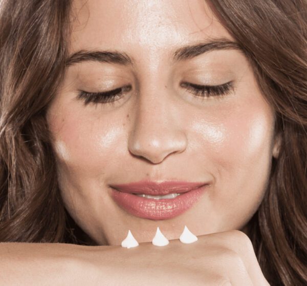 A woman is holding a piece of whipped cream on her hand.