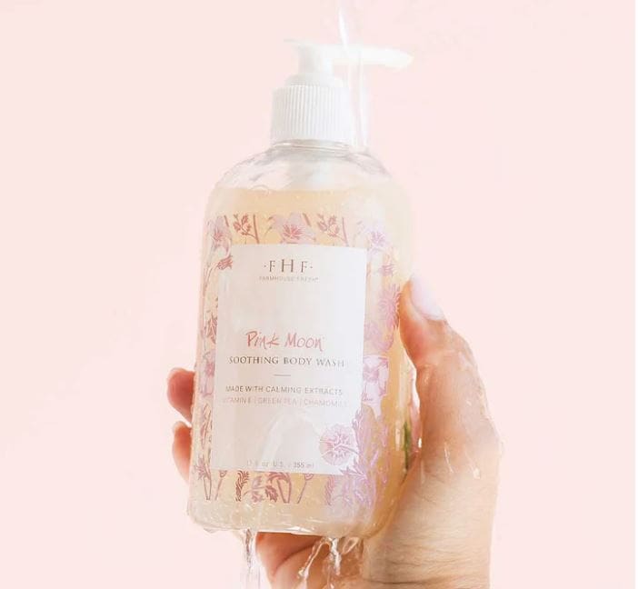A hand holding a bottle of Farmhouse Fresh Pink Moon Body Wash and Bubble Bath.