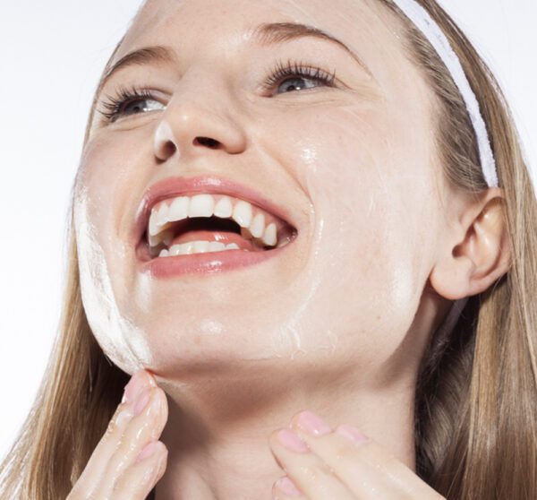 A woman is smiling with a face mask on her face.