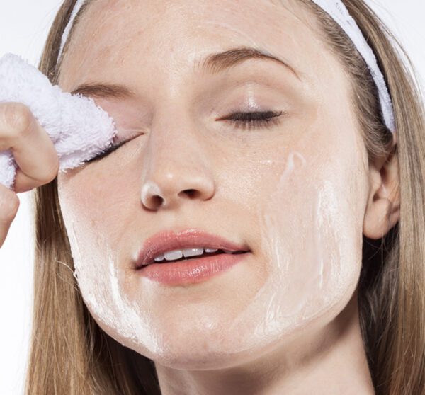 A woman wiping her face with a towel.