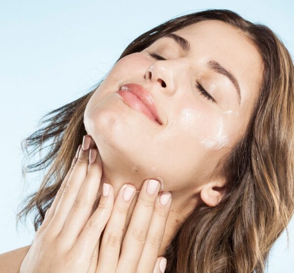 A woman is putting cream on her face.