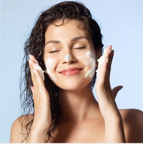 Woman washing face with foam cleanser.