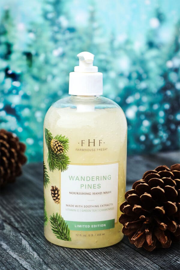 A bottle of Farmhouse Fresh LIMITED Holiday Hand & Body Wash "Wandering Pines" with pine cones next to it.