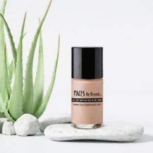 Foundation bottle beside aloe plant on stones.